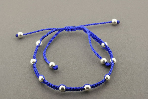 Blue bracelet with silver beads on a gray background