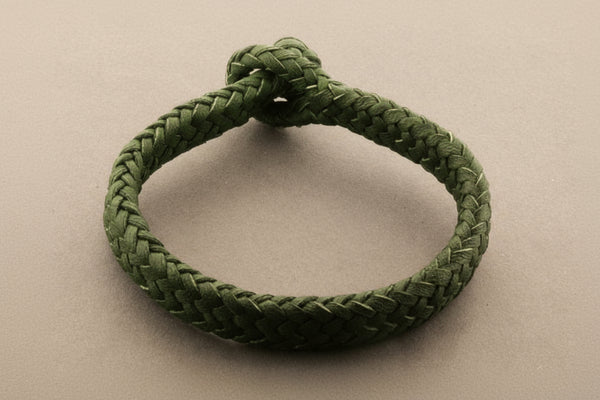Green braided bracelet on a gray background