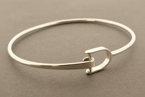 Silver bangle with a clasp on a gray background