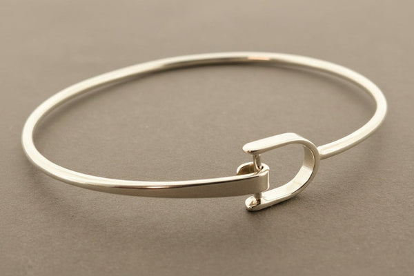 Silver bangle with a clasp on a gray background