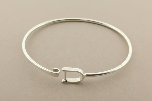 Silver bracelet with a unique clasp design on a gray background