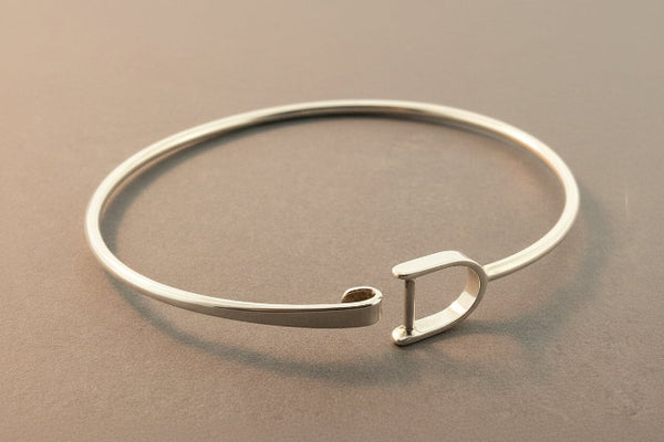 Silver bangle with a clasp on a gray background