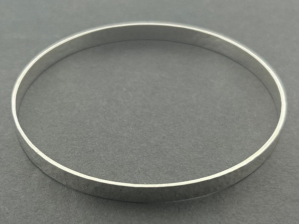 Silver bangle with a hammered treatment on a gray background