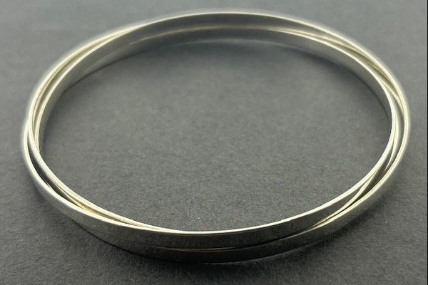 3 interlinked Silver bangle on a gray background