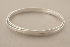 3 silver bangles on a gray background