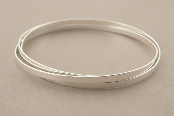 3 silver bangles on a gray background