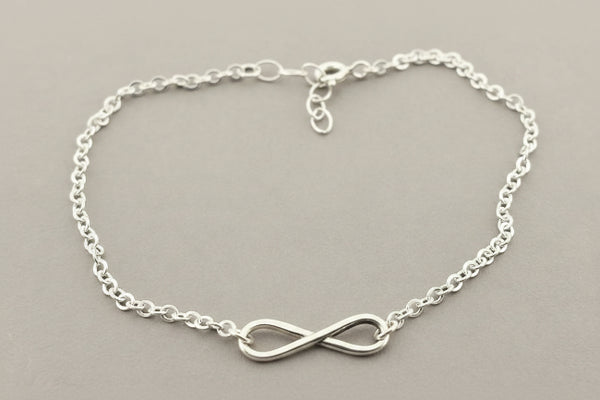 Silver infinity bracelet on a gray background