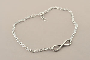 Silver chain bracelet with an infinity symbol on a gray background