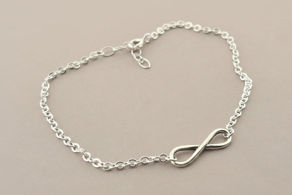 Silver chain bracelet with an infinity symbol on a gray background
