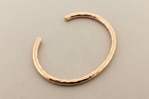 Rose gold bangle on a dark gray background