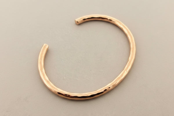 Rose gold bangle on a dark gray background