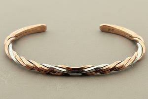 Two-tone gold and silver bracelet on a gray background