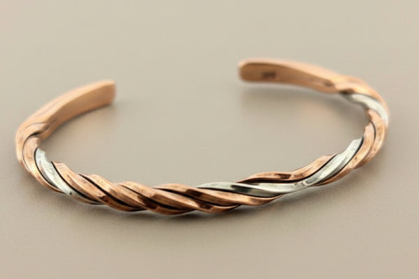 Twisted copper and silver bracelet on a gray background