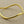 Load image into Gallery viewer, A polished gold-toned metal bangle bracelet with an organic, wavy outline, displayed on a textured gray background.

