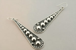 Silver earrings with geometric design on a gray background