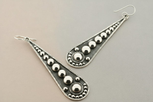 Silver earrings with geometric design on a gray background
