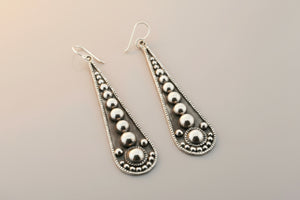Pair of silver teardrop earrings on a gray background