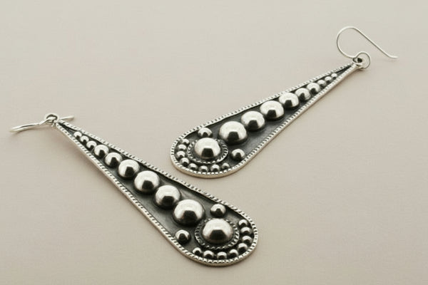 Silver earrings with decorative design on a gray background