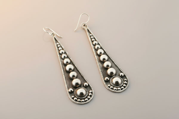 Pair of silver teardrop earrings on a gray background