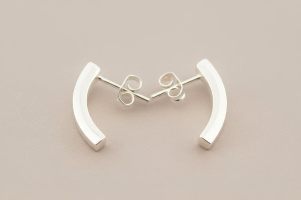 Silver curved earrings on a gray background