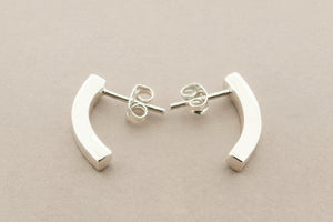 Pair of silver curved earrings on a gray background