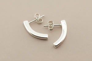Silver curved earrings on a gray background