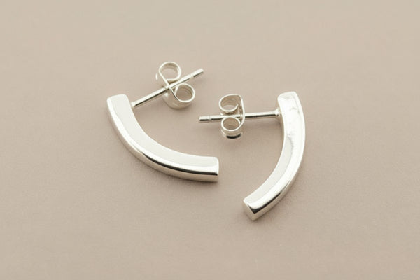 Silver curved earrings on a gray background