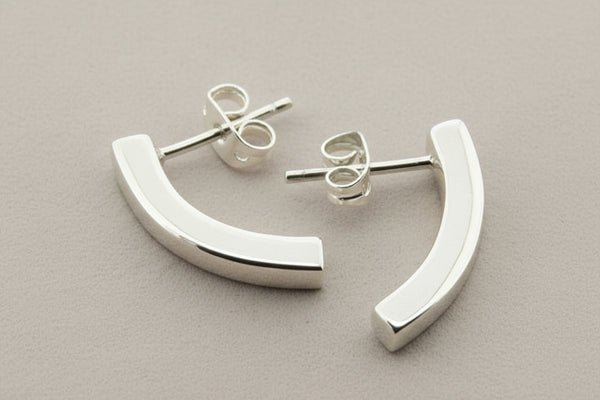 Silver half-circle earrings on a gray background