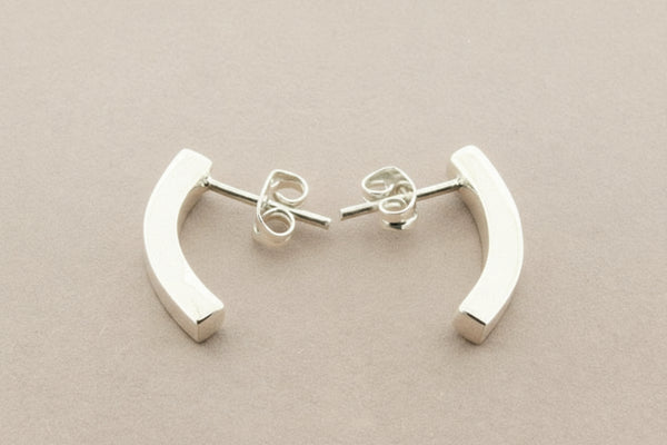 Pair of silver curved earrings on a gray background