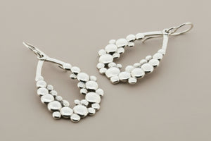 Silver earrings on a dark gray background
