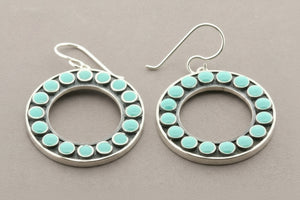 Silver hoop earrings with turquoise stones on a gray background