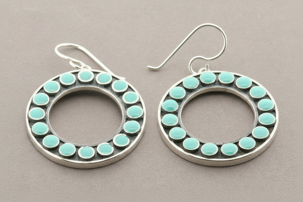 Silver hoop earrings with turquoise stones on a gray background