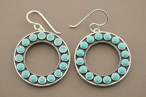 Pair of hoop earrings with turquoise beads on a gray background
