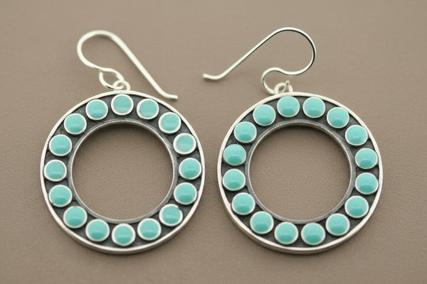 Pair of hoop earrings with turquoise beads on a gray background