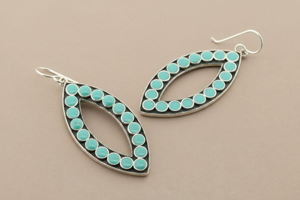 Teardrop-shaped earrings with turquoise beads on a gray background