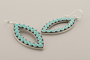 Teardrop-shaped earrings with turquoise stones on a gray background