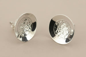 Pair of silver round earrings on a gray background