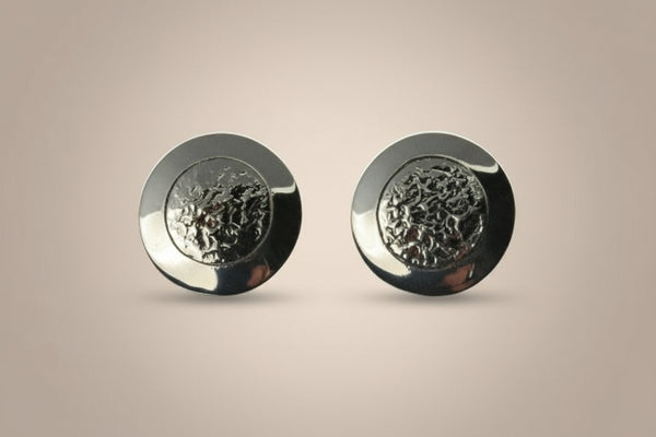 Pair of silver round earrings on a gray background