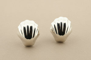 Pair of silver shell-shaped earrings on a gray background