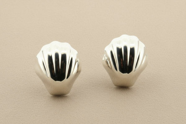 Pair of silver shell-shaped earrings on a gray background