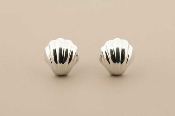 Pair of silver shell-shaped earrings on a gray background