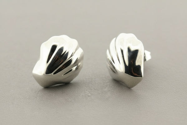 Pair of silver shell-shaped earrings on a gray background