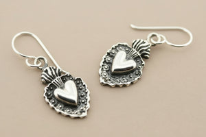Silver heart-shaped earrings on a gray background