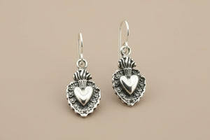 Silver heart-shaped earrings on a gray background