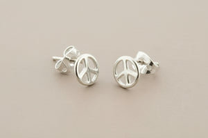 Silver peace symbol earrings on a gray background
