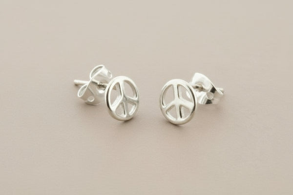 Silver peace symbol earrings on a gray background