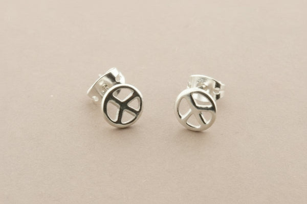 Silver peace symbol earrings on a gray background