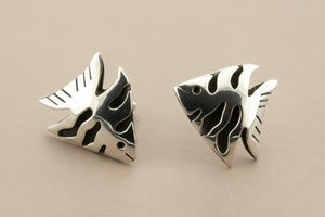 Pair of silver fish-shaped earrings on a gray background