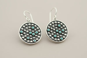 Pair of silver earrings with turquoise stones on a gray background