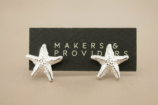 Starfish-shaped earrings on a 'Makers & Providers' card against a gray background